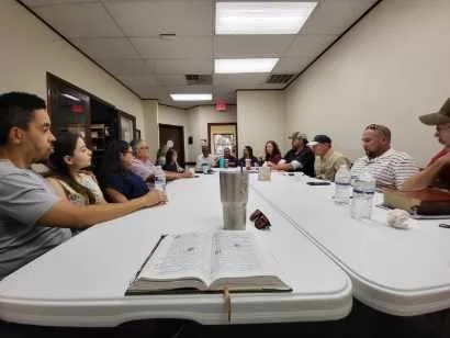 A Bible study at the Seek the City prayer room — people gathered around long tables with an open Bible in the foreground.